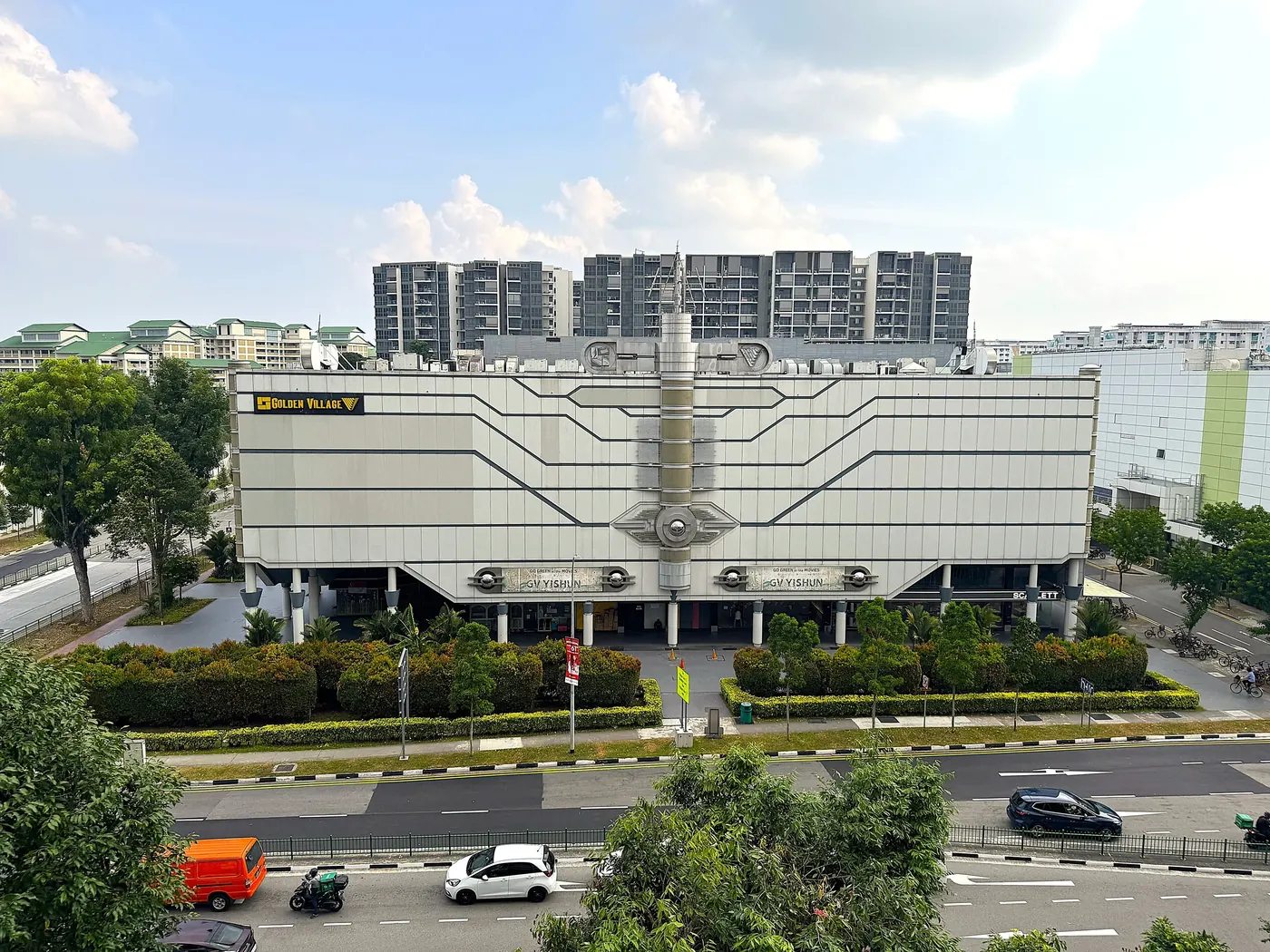 Yishun 10 today, seen from across Yishun Central: a four-storey white cinema block with Golden Village and GV Yishun signs, a planted forecourt, and the North Park Residences towers behind it